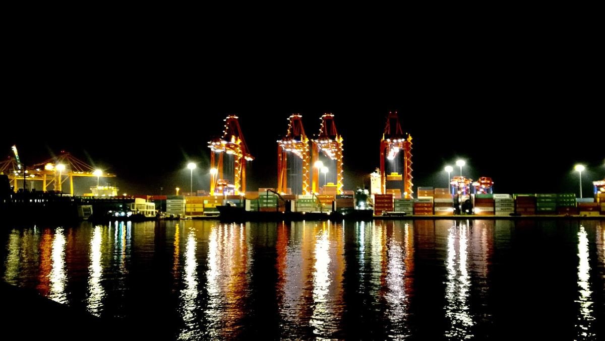 Geceleri ışıklandırılmış Mersin Limanı'nda konteyner vinçleri ve suya yansıyan ışıklar